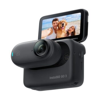 An Insta360 GO 3 action camera in black, featuring a compact design with a detachable lens module and a flip-up touchscreen display, showing a selfie image of two people and a dog on a sunny beach.